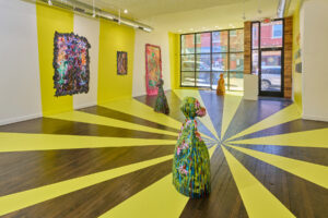 Installation of my exhibition, Present Portal. There are three large-scale ceramic works and four paintings. The floor and window are covered in yellow vinyl patterns which mimic beams of light. These beams extend to the walls where they are hand painted.