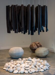 This exhibition consists of 4 installations/assemblages: 60 hanging black stoneware pipes, 350 hand-built stones piled on the floor, 3 large hand-built floor sculptures (crater glazed and sand blasted, and saggar fired), and a wall piece that is 163 components.  The exhibition references discernment and contemplative practise.

Photo credit: Alan MacNaulty