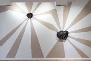 Installation view of my exhibition, The Unreal. The walls are painted with unfired clay slip. The clay beams mimic light radiating from behind each ceramic work. The beams of light are made from the same clay that the wood-fired wall pieces are made from. As the exhibition went on, the clay beams began to crack slightly. They are symbolic of the hope these wild prairie preserves bring me, yet the reality of this hope meeting constant tragedy. The back and forth that is holding and searching for hope in an often harrowing world.