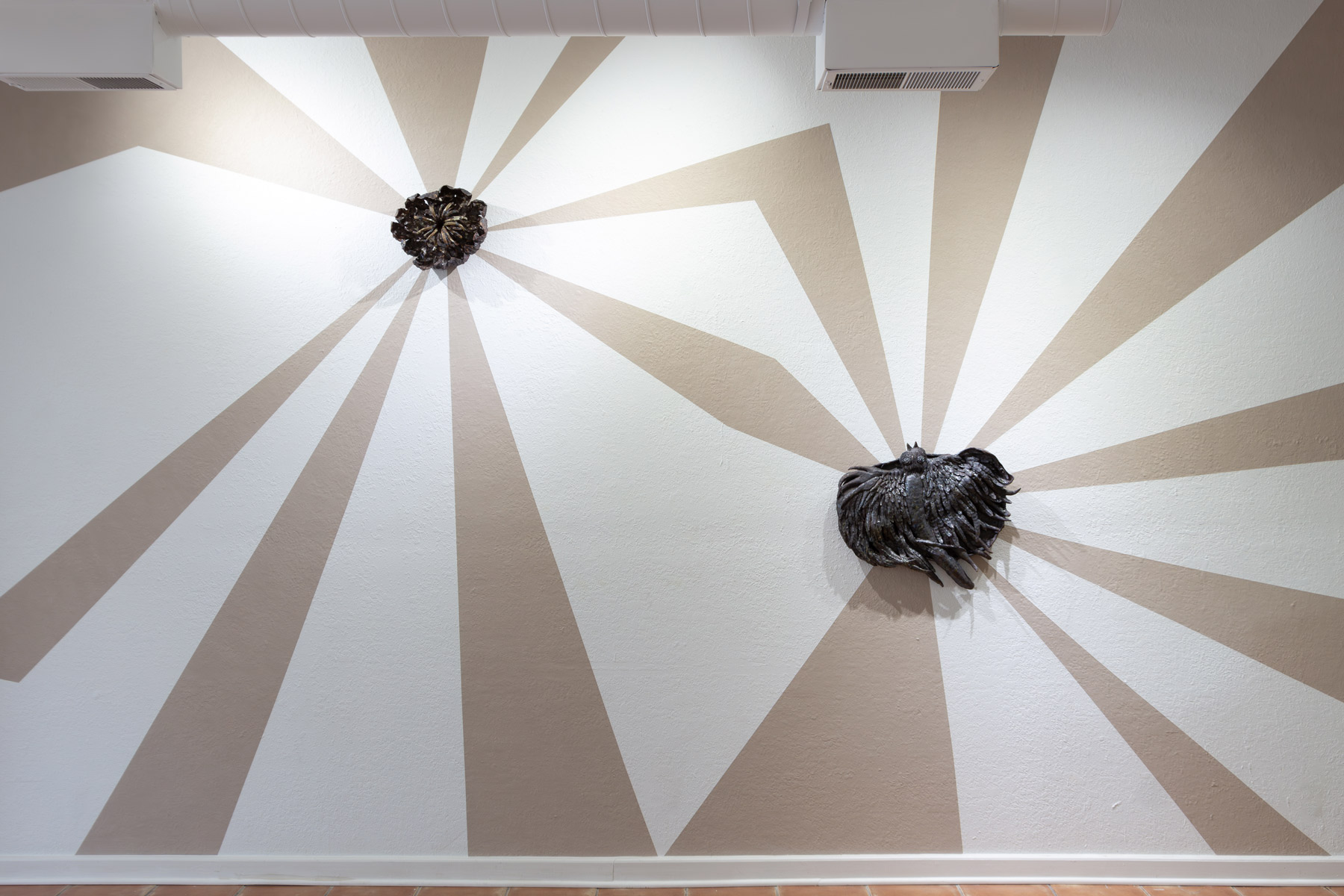 Installation view of my exhibition, The Unreal. The walls are painted with unfired clay slip. The clay beams mimic light radiating from behind each ceramic work. The beams of light are made from the same clay that the wood-fired wall pieces are made from. As the exhibition went on, the clay beams began to crack slightly. They are symbolic of the hope these wild prairie preserves bring me, yet the reality of this hope meeting constant tragedy. The back and forth that is holding and searching for hope in an often harrowing world.