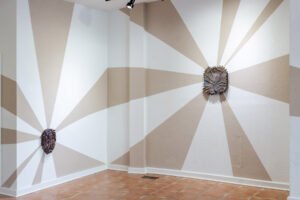 Installation view of my exhibition, The Unreal. The walls are painted with unfired clay slip. The clay beams mimic light radiating from behind each ceramic work. The beams of light are made from the same clay that the wood-fired wall pieces are made from. As the exhibition went on, the clay beams began to crack slightly. They are symbolic of the hope these wild prairie preserves bring me, yet the reality of this hope meeting constant tragedy. The back and forth that is holding and searching for hope in an often harrowing world.