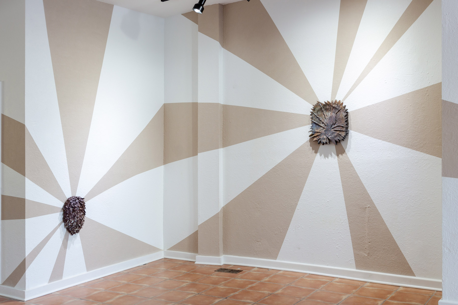 Installation view of my exhibition, The Unreal. The walls are painted with unfired clay slip. The clay beams mimic light radiating from behind each ceramic work. The beams of light are made from the same clay that the wood-fired wall pieces are made from. As the exhibition went on, the clay beams began to crack slightly. They are symbolic of the hope these wild prairie preserves bring me, yet the reality of this hope meeting constant tragedy. The back and forth that is holding and searching for hope in an often harrowing world.