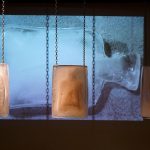 Silent Scream is a durational and immersive ceramics and video installation. The impending shatter of clay bodies frozen in ice, presents a sense of contingency and precariousness in viewers, the anticipation of fracture. As the ice melts the body of the bottle slowly reveals itself, and as if gazing into the disappearing haze of a clouded mirror you begin to see yourself: an empty vessel, headless, perhaps heedless, with gaping mouth frozen into a silent scream. Here the systemic failures, fragilities and unpredictability of living in this historical moment is felt bone-deep before the truth of it is fully, mindfully apprehended.