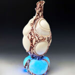 A  pitcher sits atop a porcelain platform that lights up with a controller. When the platform glows, a hidden pattern displays. The red surface is hand-painted and inspired by lattice structures found on insect wings. LED lights are hidden and connected to a rechargeable battery.