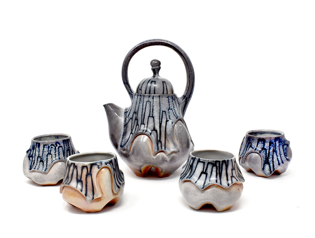 The tea set was wheel-thrown and altered, then hand-painted with colored stains. The pattern is inspired by crystalline rock formations. Fired in a wood/ soda kiln.