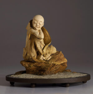 Young monk contemplating on a rock on sand