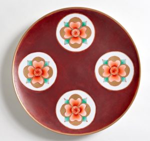 This plate features over-glaze enamels - fahong red, youhong red, fencai - and 24k gold. After reduction firing the piece was hand-painted and re-fired in multiple firing to layer on media. Original flower signifies intrinsic goodness, externally and internally.
