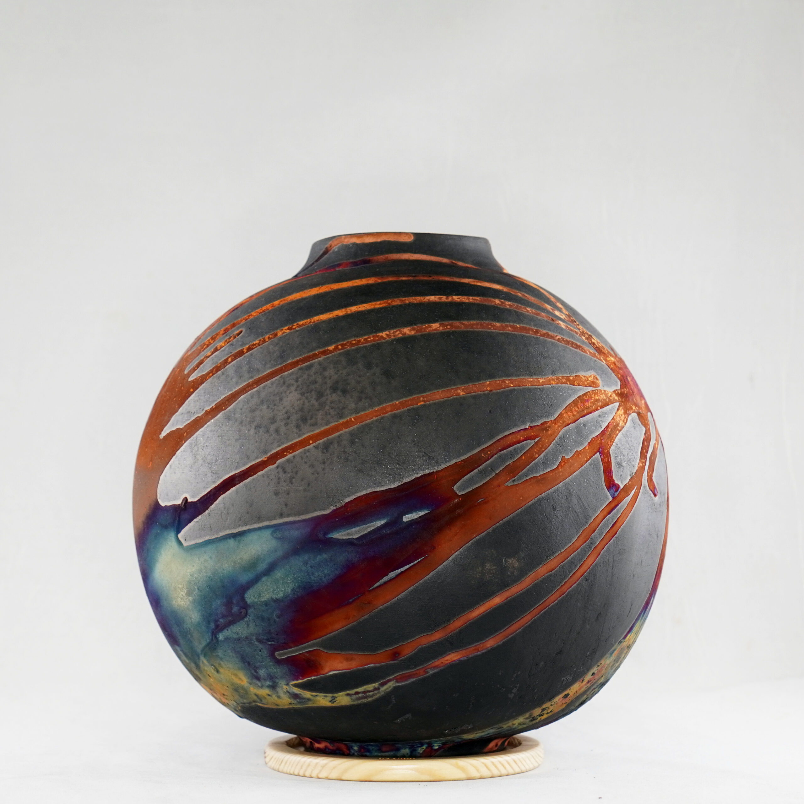 The copper matte glaze is only applied to a portion of the vase, resulting in its body being half-covered in a beautiful unexpected rainbow-like metallic finish after Raku firing. Every vase is guaranteed to be one of its kind, almost effortlessly accenting the very shape of the vase.