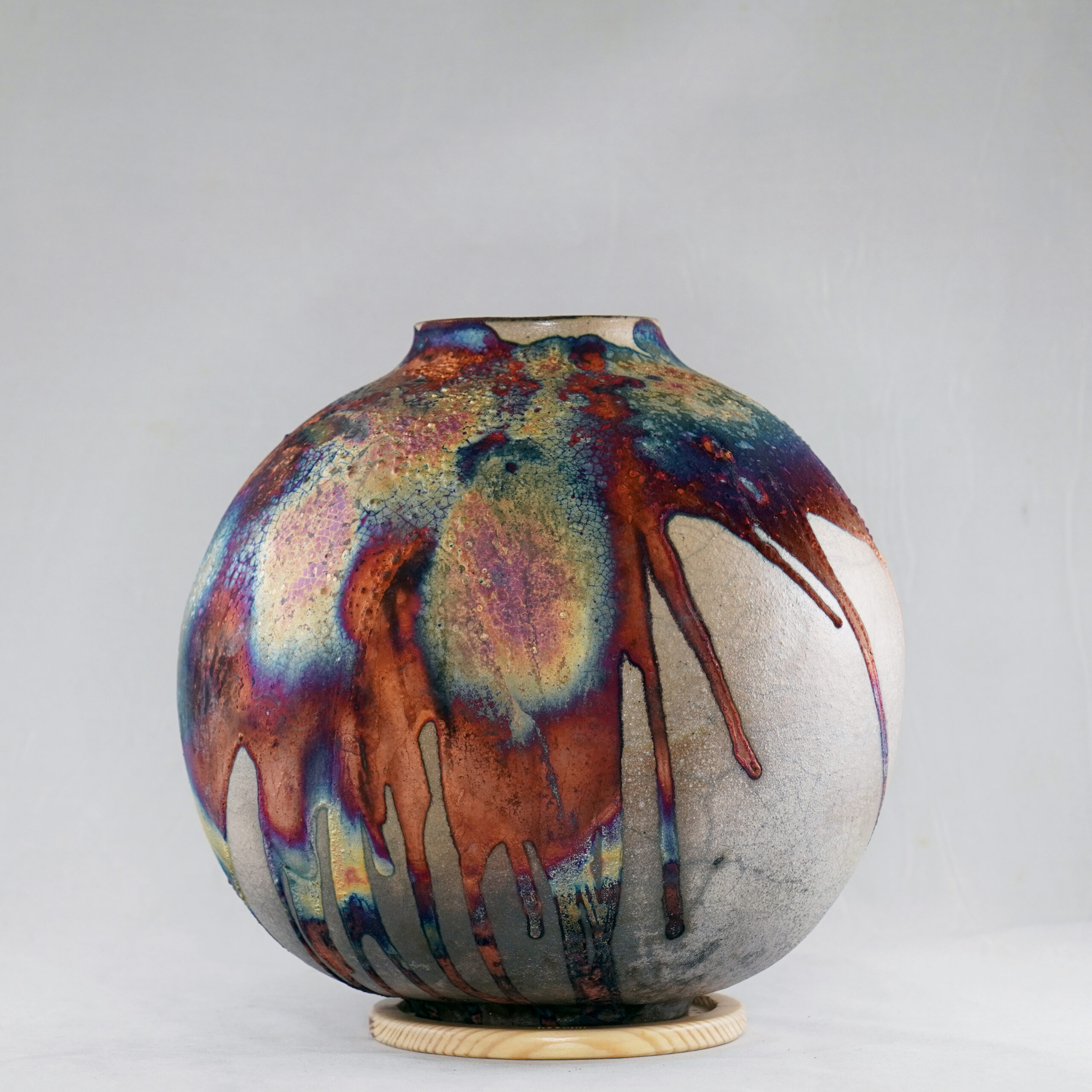 The copper matte glaze is only applied to a portion of the vase, resulting in its body being half-covered in a beautiful unexpected rainbow-like metallic finish after Raku firing. Every vase is guaranteed to be one of its kind, almost effortlessly accenting the very shape of the vase.