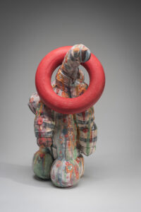 A tall sculptural object with three odd tentacles and ring hanging around the item