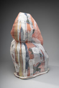 A blocky sculpture with a large fin and daubed white surface design