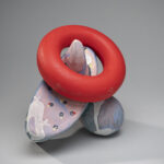 Abstract sculptural object with a large red ring dangling from a horn.