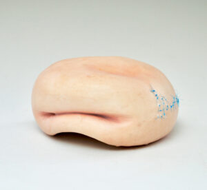The surface on the piece consists of pigmented silicone and medical sutures.
