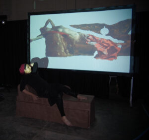 GIF animation of Benjamin-Constant's Odalisque is projected as the artist destroys a chaise longue made entirely of wet clay with her body weight.