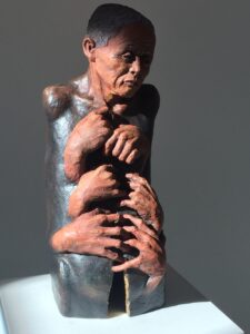 Holding describes the beauty and grace of aging. The figure has no arms or hands of its own as there is a helplessness and inability to stop the aging process. The multiple hands show a holding on of a life force or essence while the crack is a symbol of the loss of physicality. There is gold leaf at the entrance to the crack supporting the idea that the soul is the jewel. Beautiful is one who has lived through the tibulations of time but continues to sparkle with the hope and shine of life.