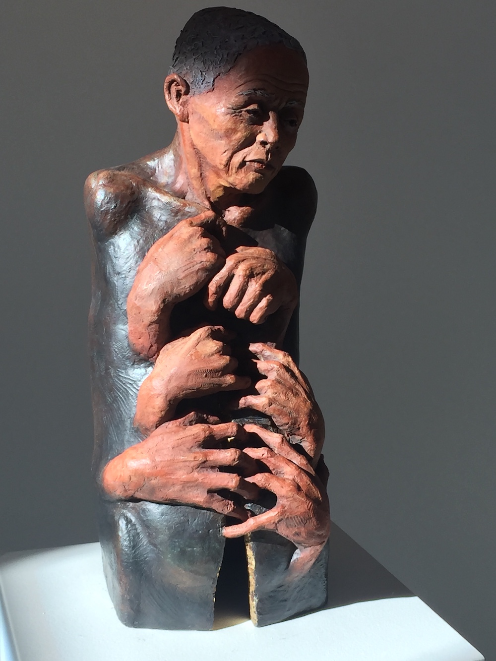 Holding describes the beauty and grace of aging. The figure has no arms or hands of its own as there is a helplessness and inability to stop the aging process. The multiple hands show a holding on of a life force or essence while the crack is a symbol of the loss of physicality. There is gold leaf at the entrance to the crack supporting the idea that the soul is the jewel. Beautiful is one who has lived through the tibulations of time but continues to sparkle with the hope and shine of life.