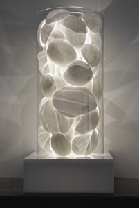 slip cast organic forms are contained in a borosilicate cylinder, resting upon a fabricated plastic light box