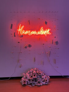 porcelain, neon, plexi: thread red neon text, loose porcelain 'curtain' of pills, flowers, and masks, flowing into pyramid of porcelain dipped skulls and thistles 
Tlamanalisti is the Nahuatl (Uto-Aztecan) word for the ritual of sacrifice. This piece refers to the frequent messaging that vulnerable groups should ‘be sacrificed’ during the pandemic in exchanged for a return to normalcy.