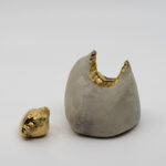 Or 'Midas's Touch'  takes its inspiration from the Phrygian king whose golden curse originated across the
Aegean from Rhodes, in the mythological landscape of Anatolia. A lump of wedged earthenware
holds a single bite: teeth meeting clay in the body's most intimate gesture. The impression is sealed
in transparent glaze and 14ct gold lustre; the expelled fragment, equally gilded, lies beside it. Midas
could not eat, could not embrace. When touch becomes a transaction, even appetite turns to
currency.