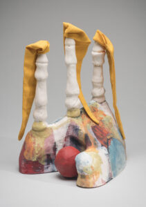 A small mounded sculture with with three spires each containing a droopy yellow pennant flag