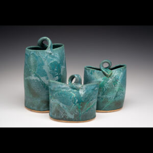 These vases are thrown and altered with textured slab bases. Stain is added to the bases and wiped off to stay in texture. Handles are pulled. Turquoise glaze is mixed up in studio and poured and dipped and other glazes are added. I fire to Cone 6 in oxidation with a 20 minute hold.