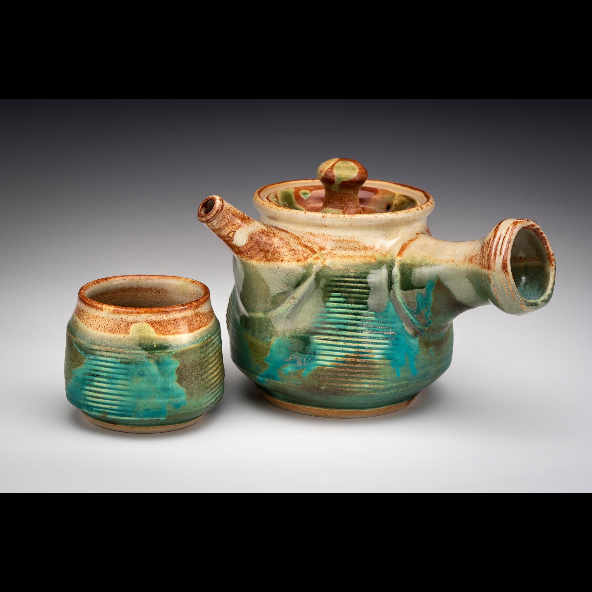 Teapot and yunomi are thrown and altered by paddling after throwing. Kyusu handle and spout  are thrown separately and added after trimming foot. Teapot and yunomi are white stoneware and fully functional. Teapot has strainer holes under the thrown spout and steam hole in lid. They are microwave and dishwasher safe.