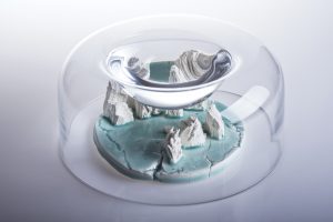The collection consists of glass objects inside which there are porcelain landscapes. The water in the cavity of the glass form creates a magnifying glass, which allows to look closely at the micro-landscape, but prevent from touching them. Hiding the islands under cloaks may suggest danger, isolation and exclusion of this fragment of nature. It may also mean that it is hidden as the last parts of the world undamaged by humans. Is there still a place on Earth where man has not left his mark?