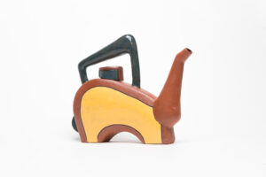The spout is wheelthrown, but the rest was built with slabs. Most of it is unglazed with terra sigilata, there is a portion glazed yellow with a black inlayed line surrounding it. Cone 1.