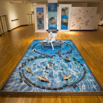 2014, Glazed and painted earthenware, glazed porcelain, photomontages on fabric, metal, wood, 121” h x 144” w x 240” d. Photo credit – Allen Cheuvront. (On exhibition at the Samuel P. Harn Museum of Art)