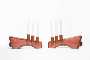 The parts of the candelabra that hold the candles are wheelthrown, then attached to a larger handbuilt form. The majority of this piece is unglazed with terra sigilata, the remaining parts are glazed mauve. There is a black inlayed line surrounding the glazed portion. Cone 1.