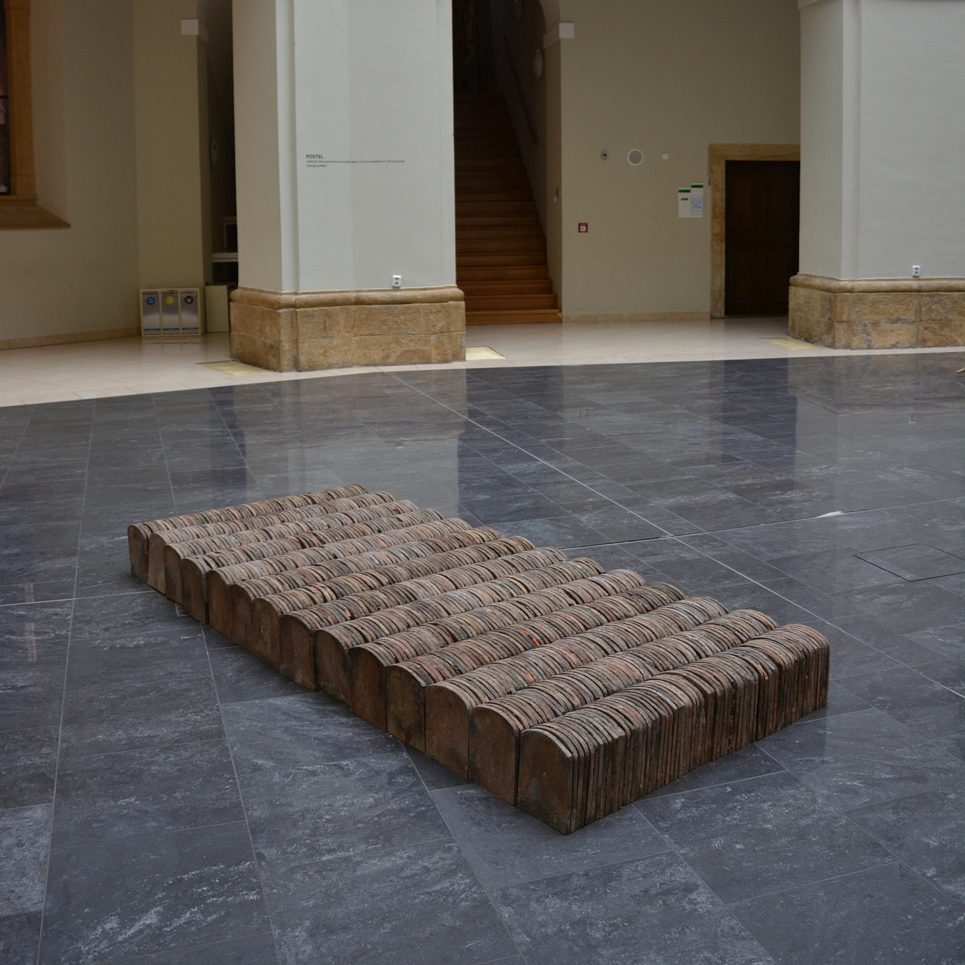 All the tiles were collected from a roof of an old house, which was condemned to demolition. Its smashed and shattered roof becomes rearranged and pieced back together to a symbolic bed – a site of rest, birth or death. Bed that incorporates the most intimate moments of life and presents a sort of tiny dwelling in the midst of a house.
