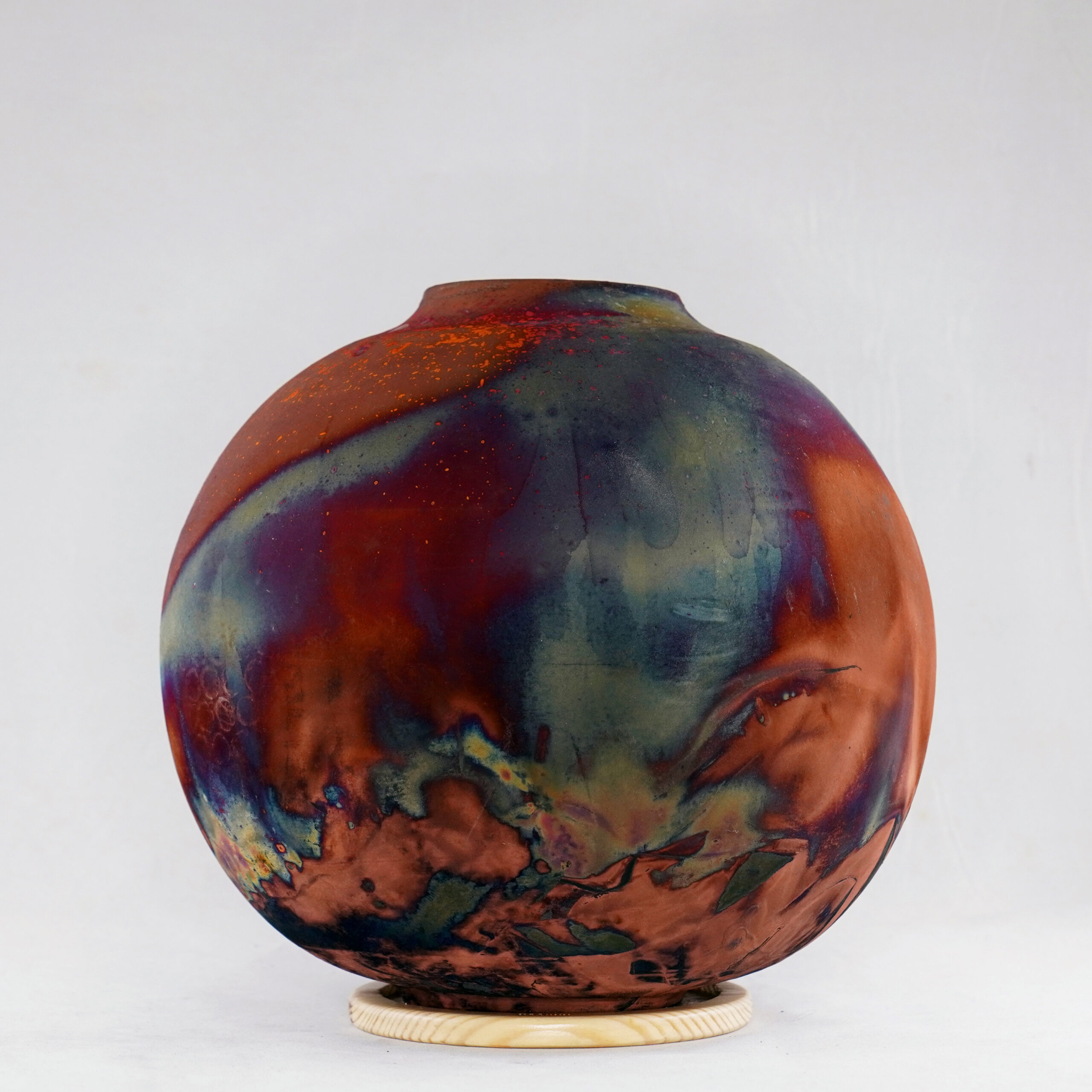 The full copper matte glaze provides a striking finish to the vase, making it an instant contrast to any interior. With an iridescent splash of metallic-like colors and unique patterns covering the vase’s body after Raku firing, no two pieces are the same.