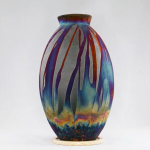 The copper matte glaze is only applied to a portion of the vase, resulting in its body being half-covered in a beautiful unexpected rainbow-like metallic finish after Raku firing. Every vase is guaranteed to be one of its kind, almost effortlessly accenting the very shape of the vase.