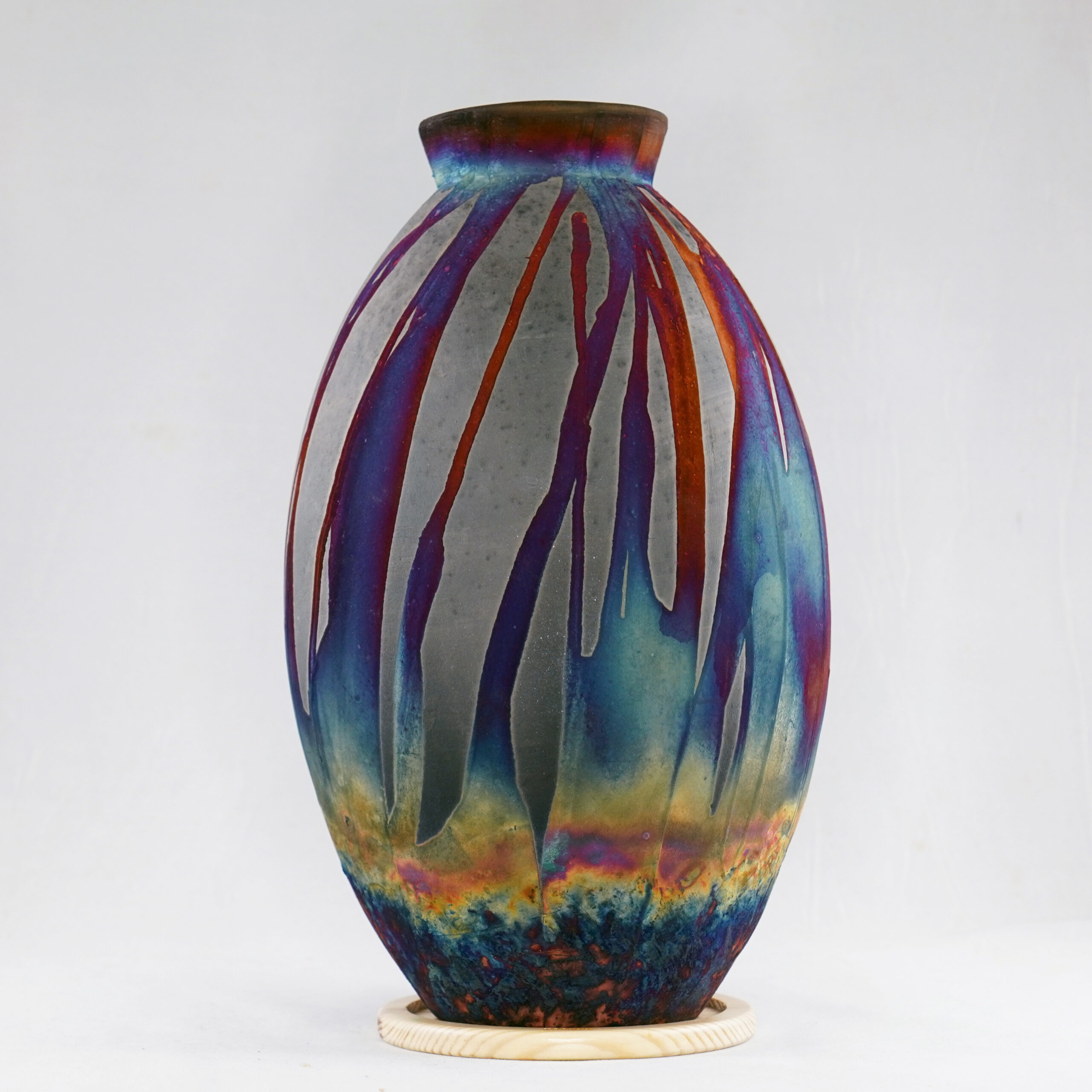 The copper matte glaze is only applied to a portion of the vase, resulting in its body being half-covered in a beautiful unexpected rainbow-like metallic finish after Raku firing. Every vase is guaranteed to be one of its kind, almost effortlessly accenting the very shape of the vase.