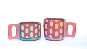 The handles are made from slabs. The unglazed surfaces have terra sigilata, the glazed portions are surrounded by inlayed black lines. Cone 1.