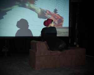 GIF animation of Benjamin-Constant's Odalisque is projected as the artist destroys a chaise longue made entirely of wet clay with her body weight.