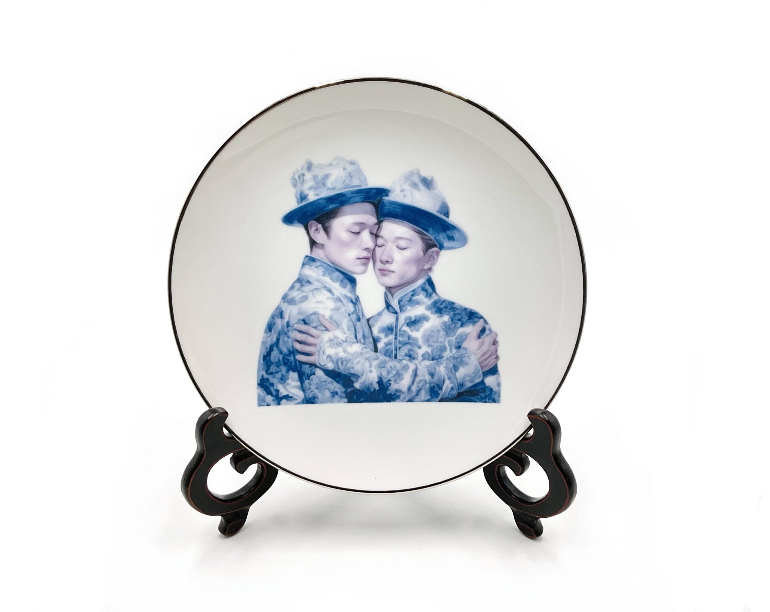 porcelain plate on wood stand depicting two men embracing