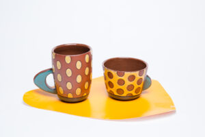 The handles are made from slabs. Terra sigilata with glaze and inlayed black lines surrounding each glazed part. Cone 1. Decorative Vinyl on the bottom just for the picture.
