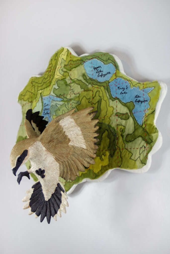 wall hanging sculpture of a ceramic bird and fabric map